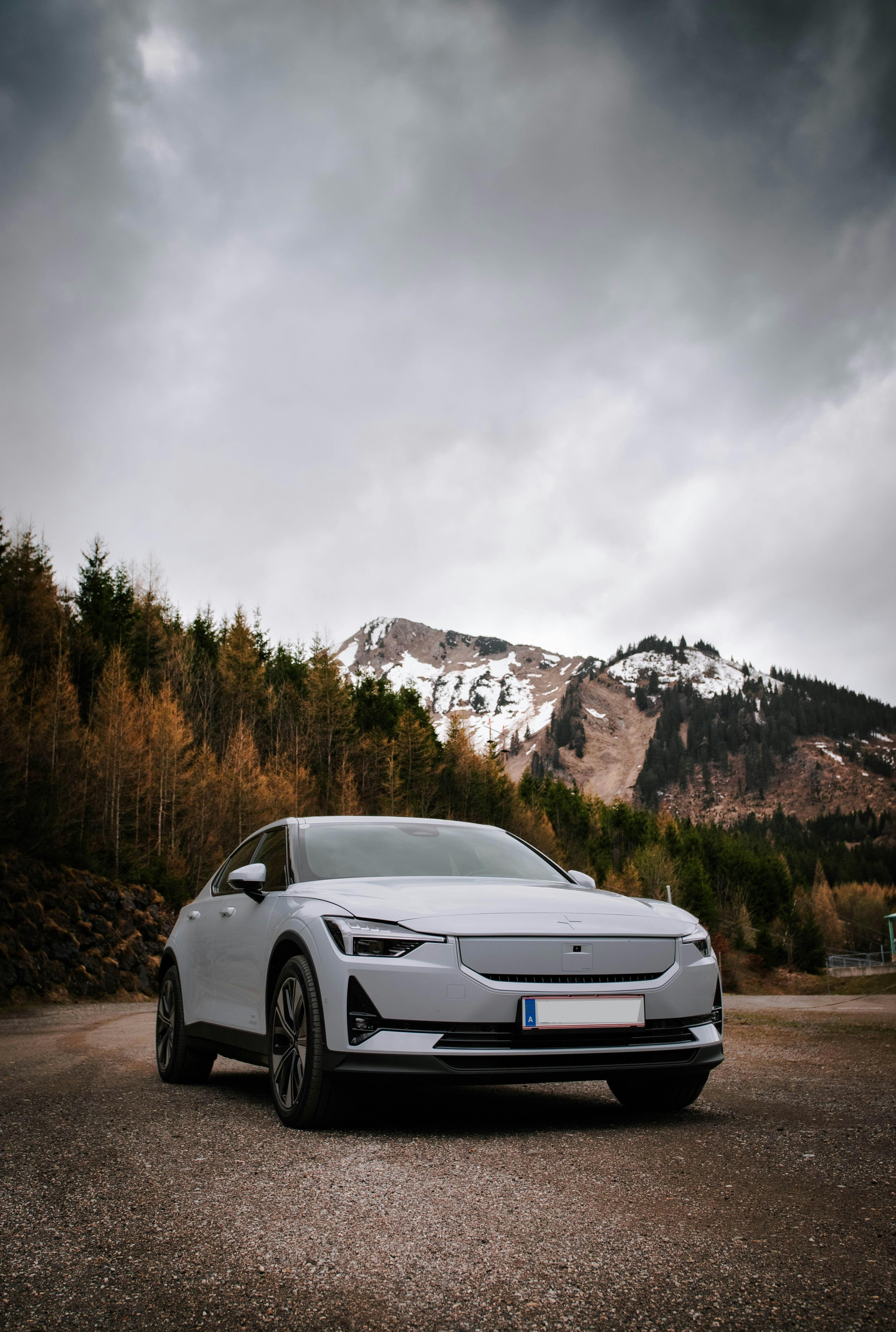 A white BYD Atto 3 electric SUV parked with a scenic mountain backdrop.